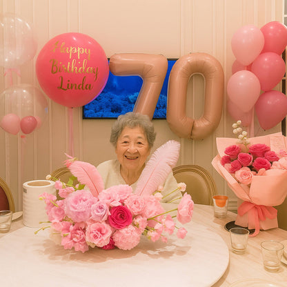 Woman celebrating her 70th birthday with pink balloons and flowers.
