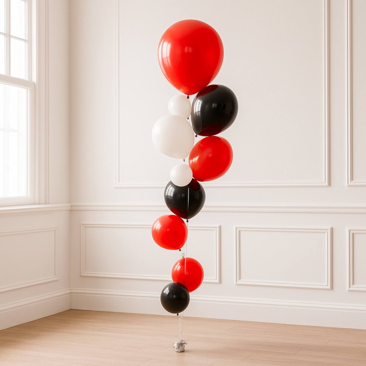 Red, black, and white balloons arranged vertically against a white paneled wall.