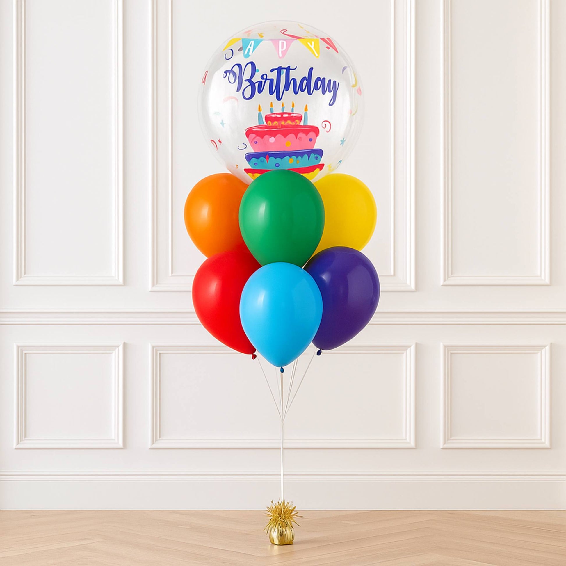 Colorful balloons with a birthday cake design against a white paneled wall.