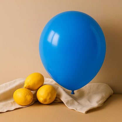 Blue 11 inch helium balloon and lemons on a beige surface with a beige background