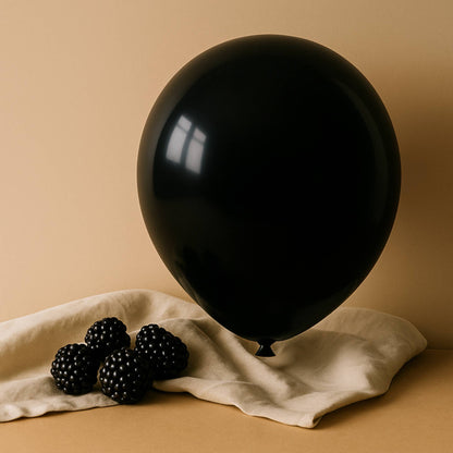 Black balloon and blackberries on a beige cloth against a beige background