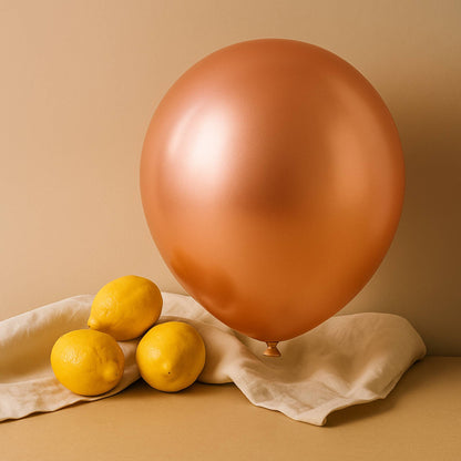 Bronze 11 inch helium balloon and lemons on a beige cloth against a beige background