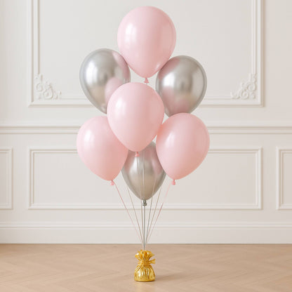 Bunch of pink and silver balloons on a stand against a white wall.