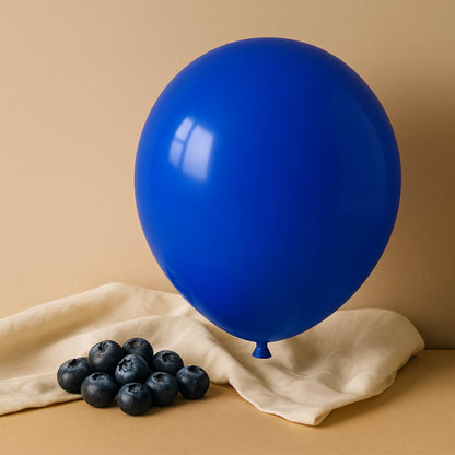 Blue 11 inch helium balloon and blueberries on a beige cloth against a beige background