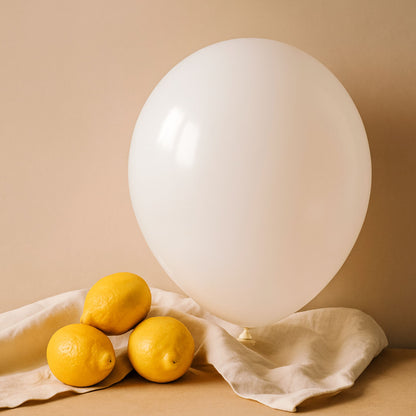 White balloon and lemons on a beige surface with a beige background