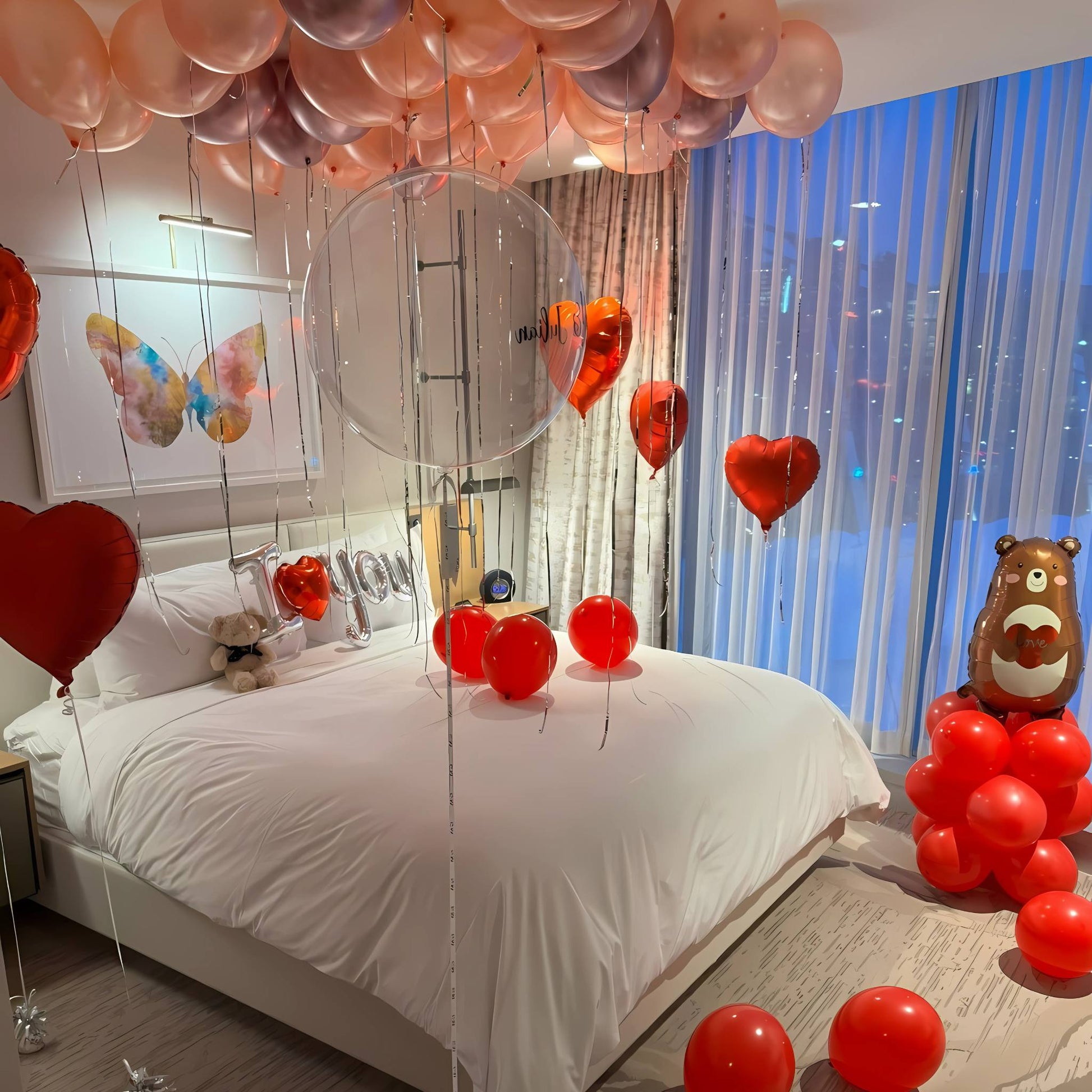 Decorated bedroom with balloons and teddy bears, featuring a large mirror and cityscape view.