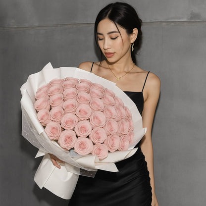 Woman holding a large bouquet of pink roses against a gray background