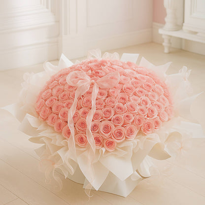 Heart-shaped arrangement of pink roses with white ribbons on a light wooden floor.