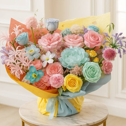 Bouquet of colorful flowers wrapped in yellow paper on a marble surface.