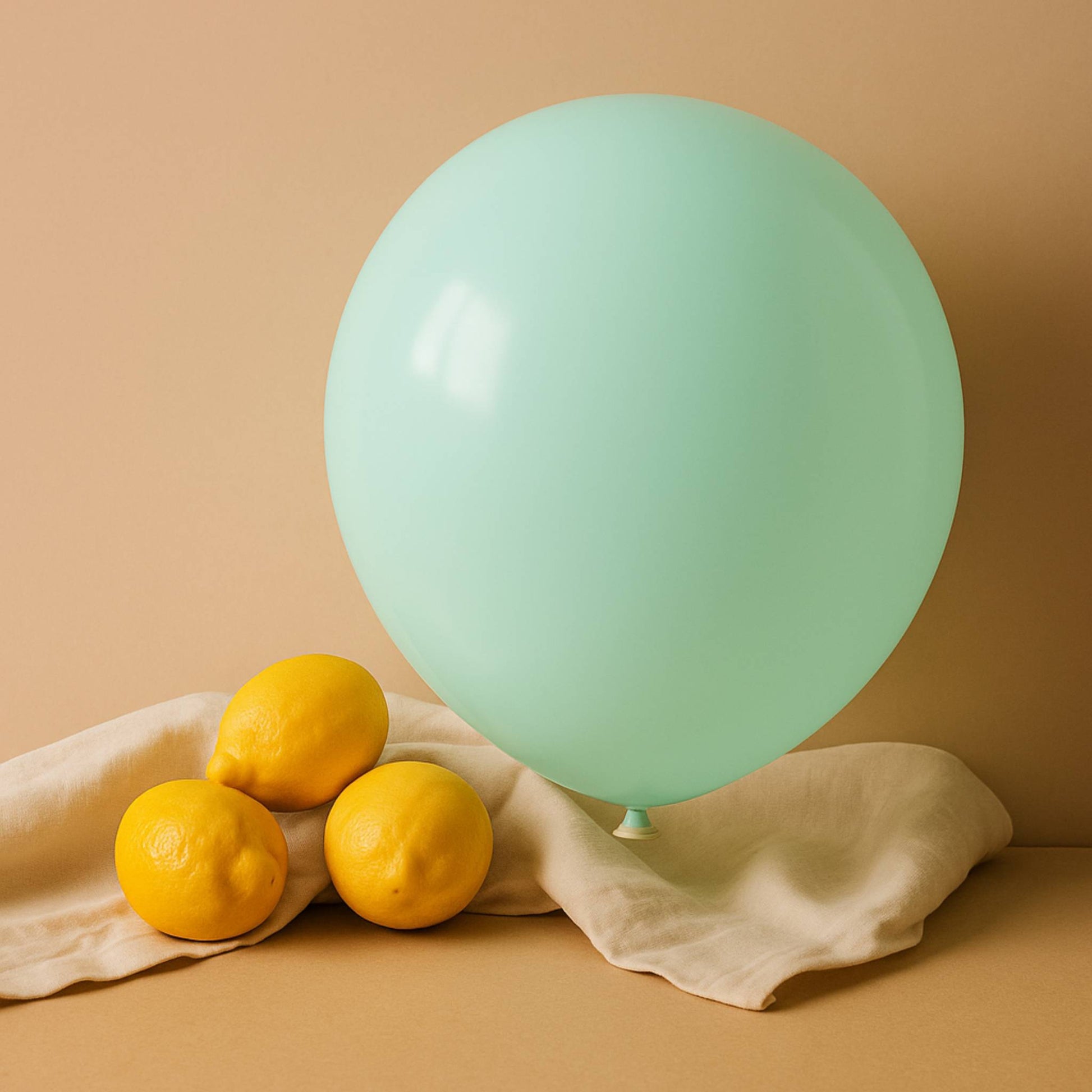 Green balloon and lemons on a beige cloth against a beige background