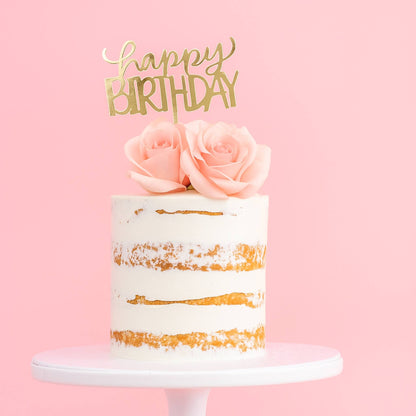 Birthday cake with gold accents and pink roses on a pink background