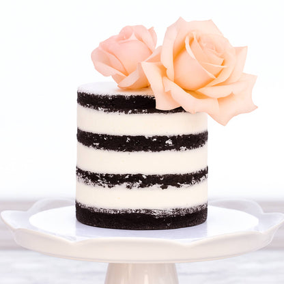 Small cake with black and white stripes and pink roses on a white background