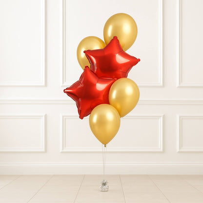 Bouquet of red and gold balloons against a white paneled wall.