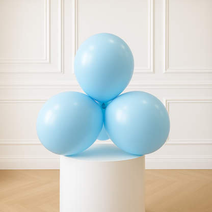 Three light pastel blue balloons on a white pedestal against a white paneled wall.