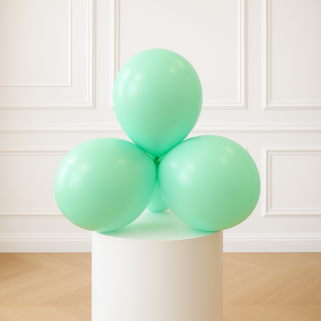 Three pastel green balloons on a white pedestal against a white paneled wall.