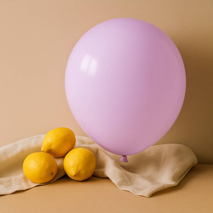 Pink 11 inch helium balloon and lemons on a beige cloth against a beige background