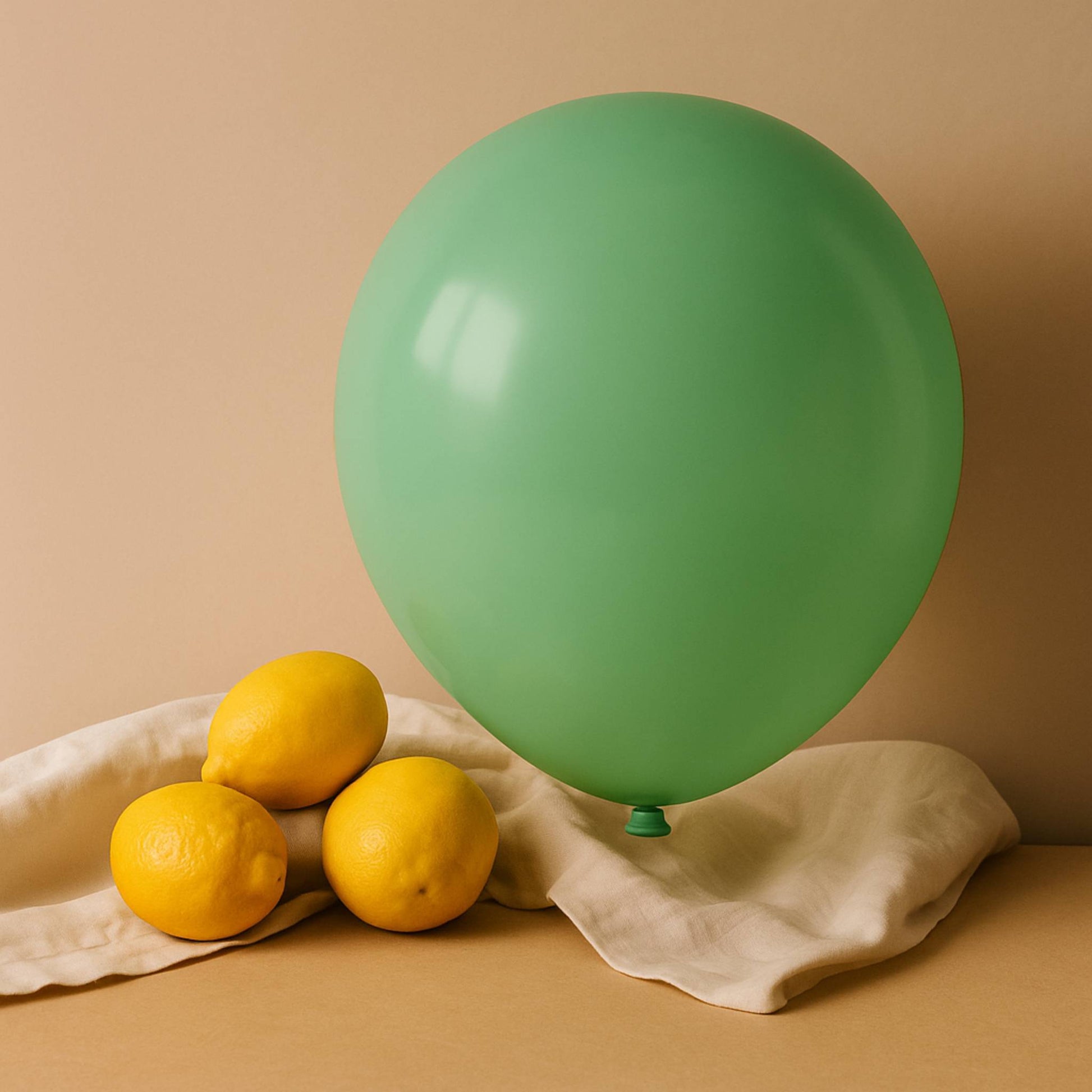 Green balloon and lemons on a beige cloth against a beige background