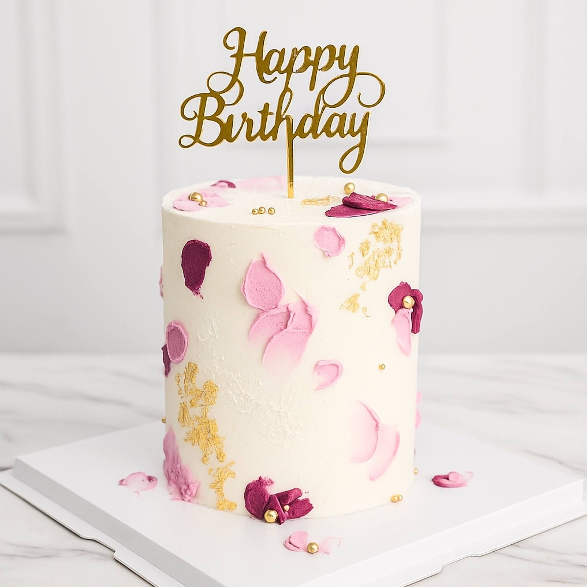 Birthday cake with floral decorations and a 'Happy Birthday' topper on a white background