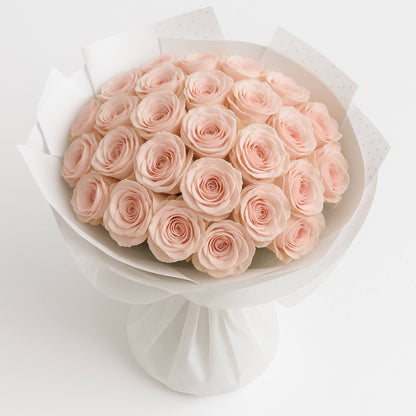 Bouquet of pink roses wrapped in white paper on a light gray background