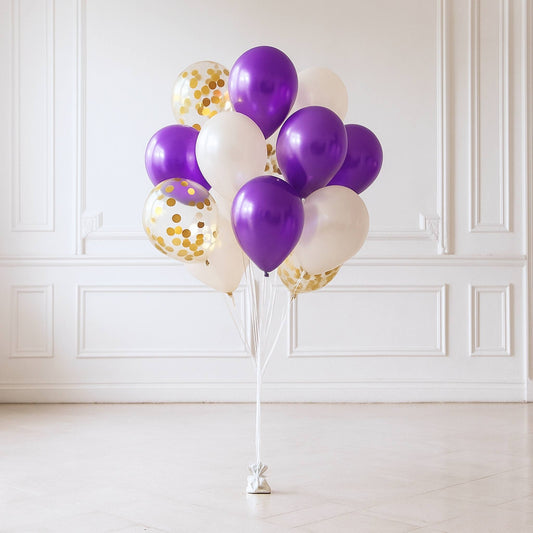 Bouquet of purple, white, and gold balloons on a stand against a white wall.