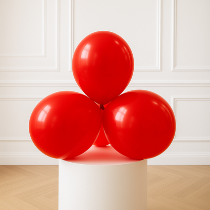 Red balloons on a white pedestal against a white paneled wall.
