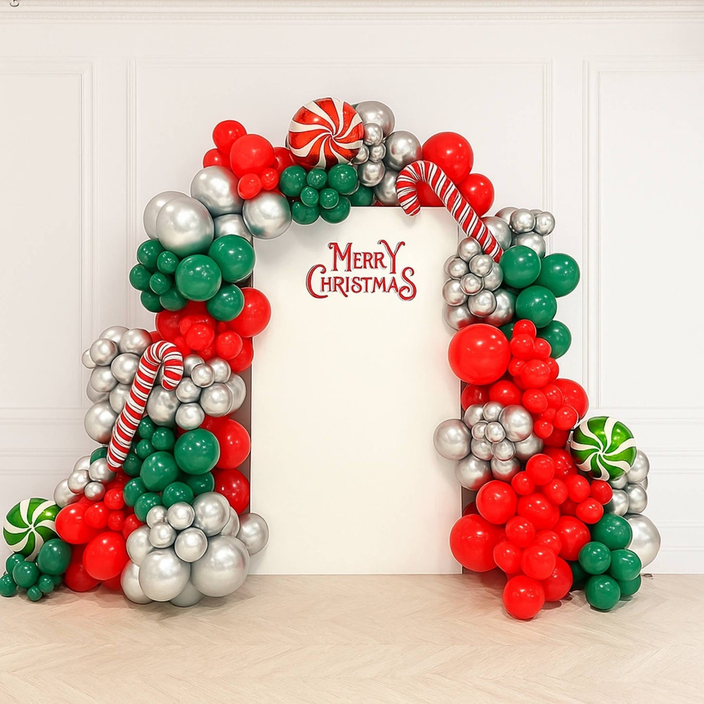 Christmas-themed balloon arch with 'Merry Christmas' text on a white wall.