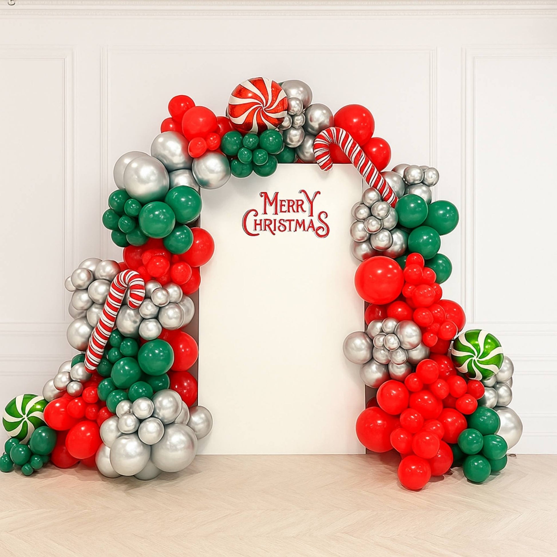 Christmas-themed balloon arch with 'Merry Christmas' text on a white wall.