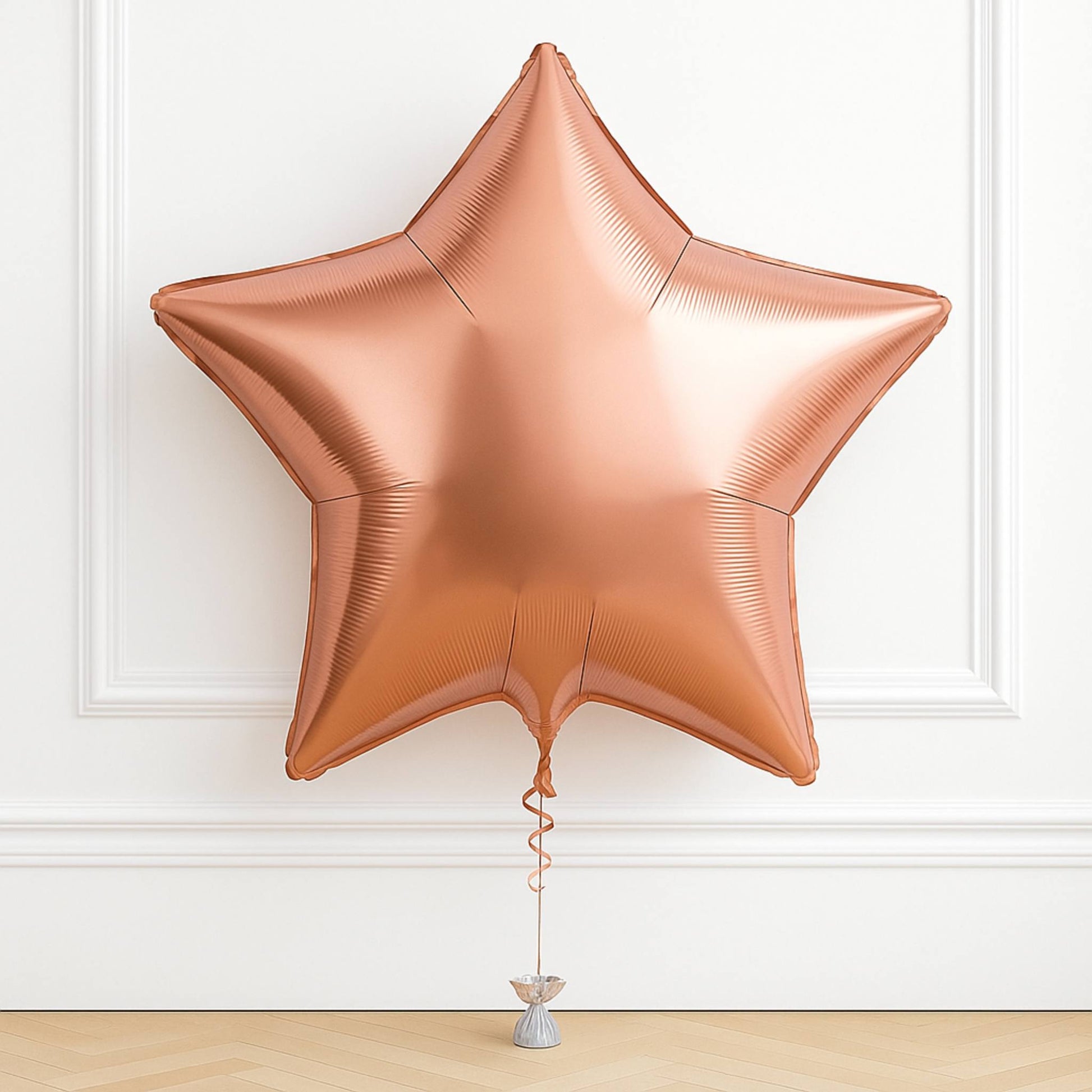 Rose gold star-shaped balloon on a white wall background