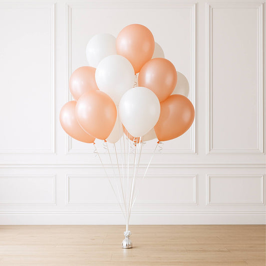 Bunch of peach and white balloons against a white paneled wall.