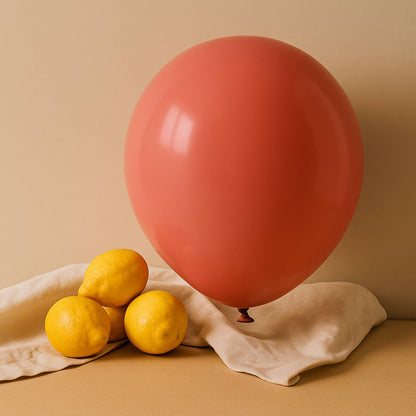 Red 11 inch helium balloon and lemons on a beige surface with a beige background