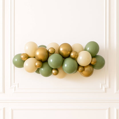 Balloon garland in gold, green, and beige on a white wall
