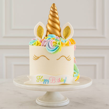 Unicorn-themed birthday cake with colorful decorations on a white stand.