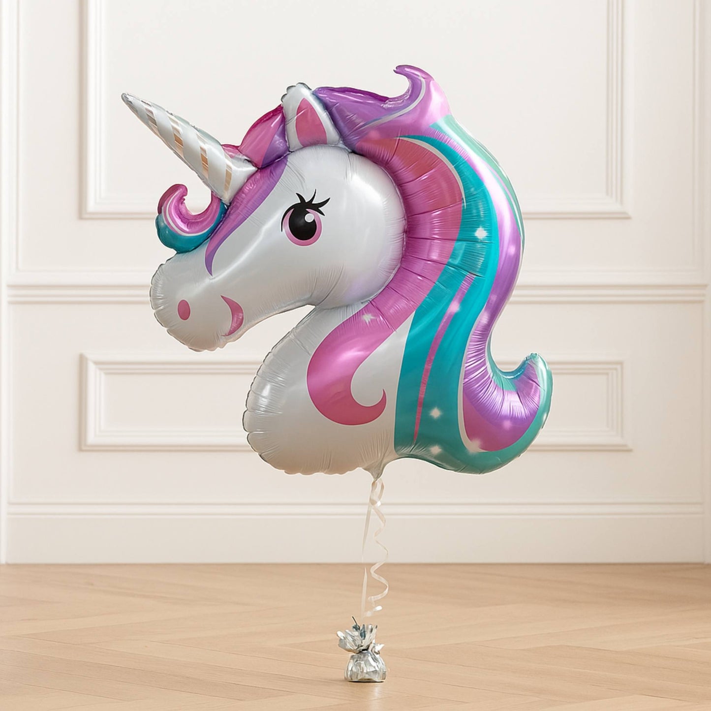Unicorn-shaped balloon with colorful design on a wooden floor.