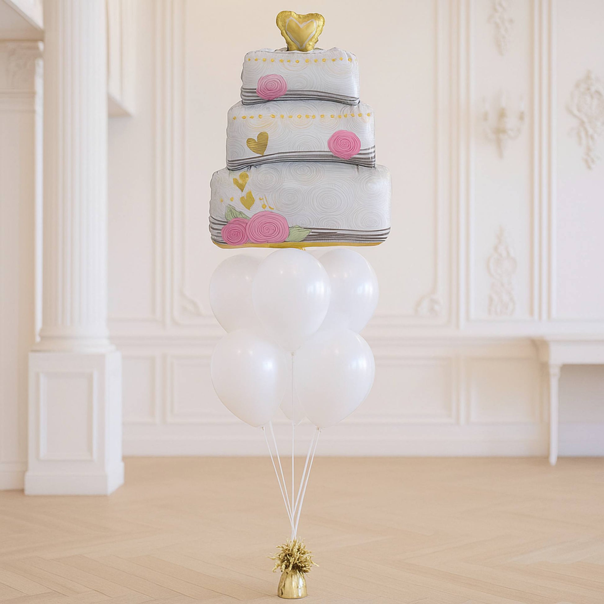 Balloon sculpture of a multi-layered cake with decorative elements on a white background