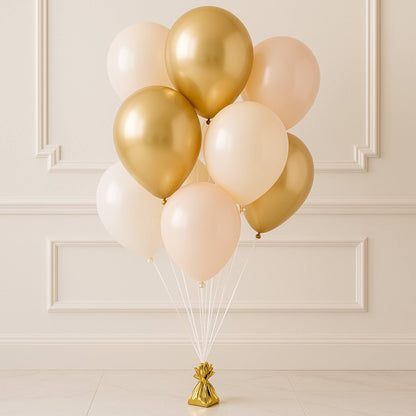 Bouquet of gold, white, and pink balloons against a beige wall.