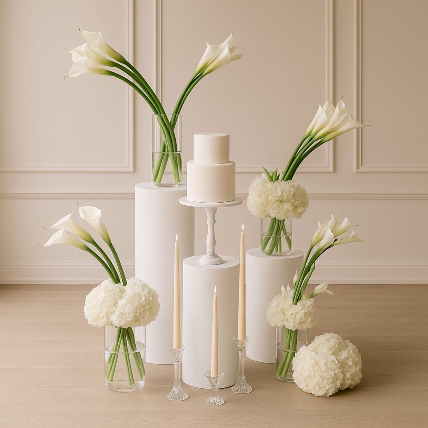 Decorative setup with white flowers, a cake, and candles on a wooden floor.