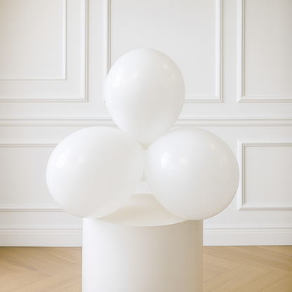 Modern white sculpture 11 inch balloons with spherical design on a pedestal against a white paneled wall.