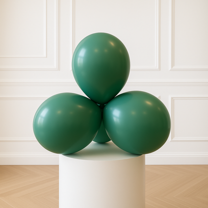 Three green balloons on a white pedestal against a white paneled wall.