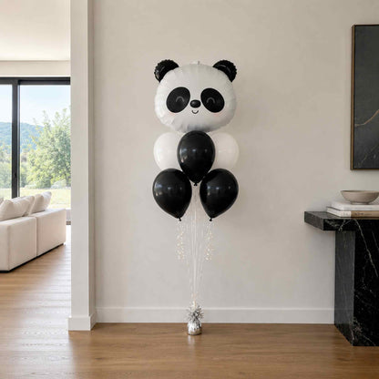 Panda-shaped balloon with black and white balloons in a living room setting