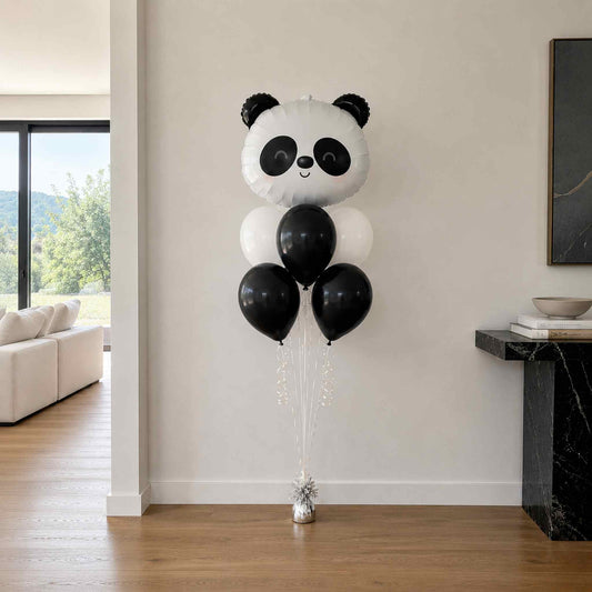 Panda-shaped balloon with black and white balloons in a living room setting