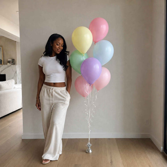 Woman holding pastel balloons in a room with a couch and marble fireplace.