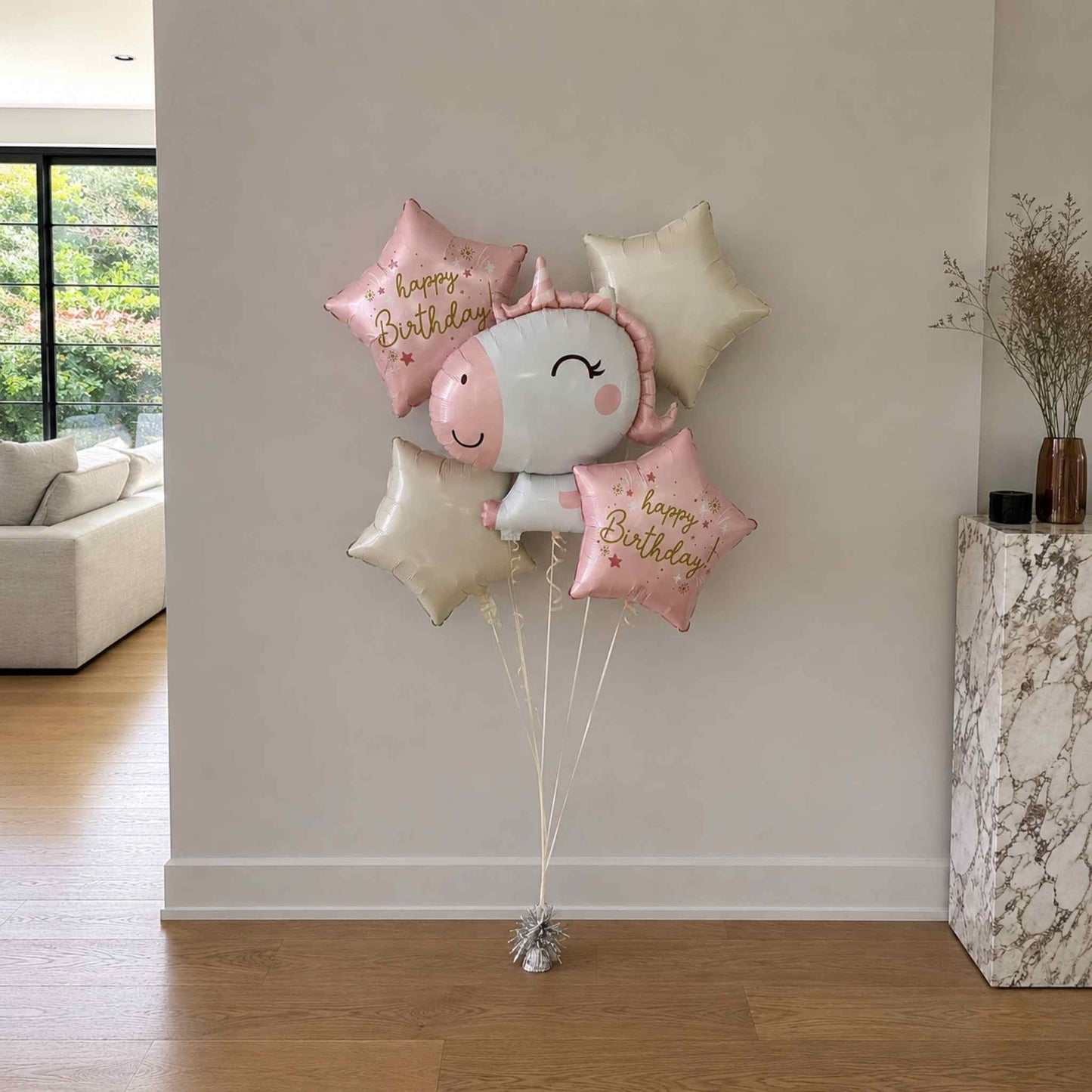 Set of balloons with a smiley face balloon and 'Happy Birthday' text in a living room setting.