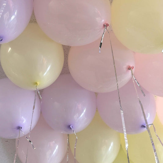 Close-up of pastel-colored balloons with string decorations against a neutral background