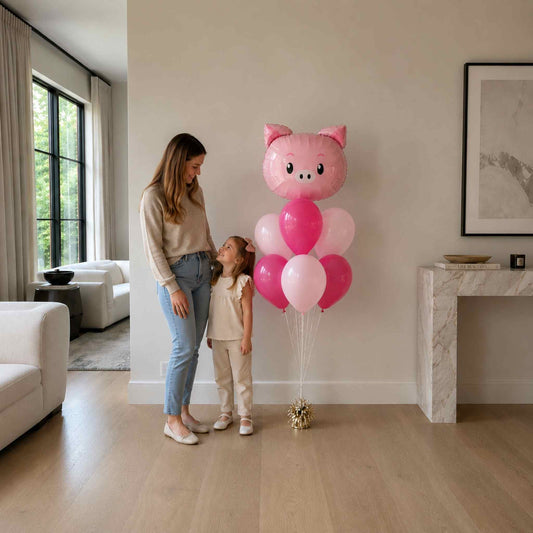 Woman and child standing next to a large pink balloon sculpture in a living room.
