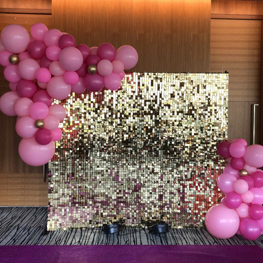 Decorative setup with pink balloons and a glittery backdrop in a room.