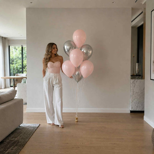 Woman holding pink and silver balloons in a modern living room.