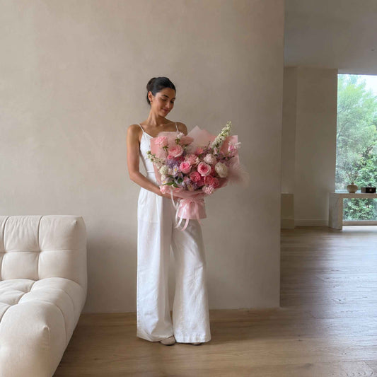 Pink roses with flower assortments. Woman holding the bouquet inside a large apartment space