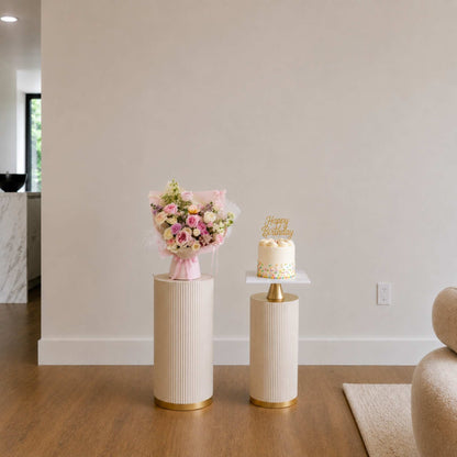 Two small decorative tables with a bouquet of flowers and a small cake in a room.