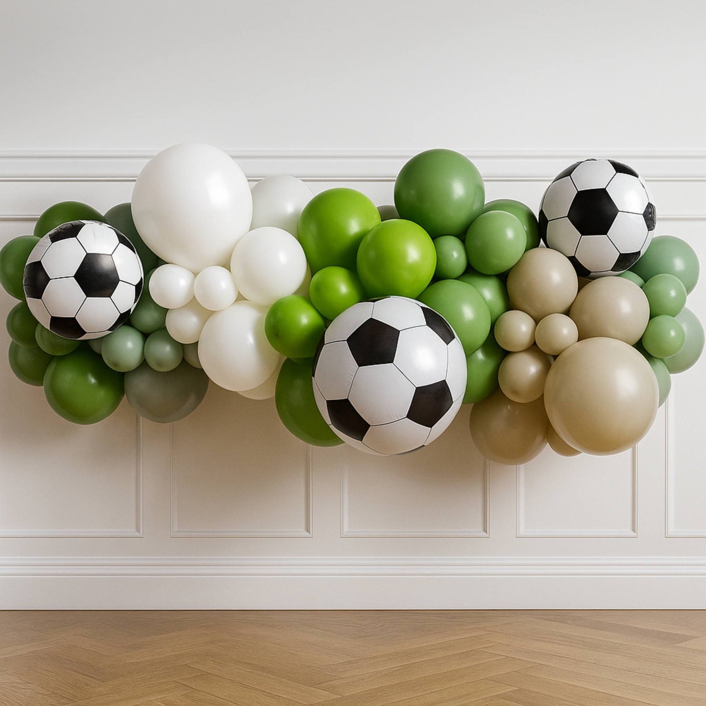 Balloon arch with soccer ball designs against a white wall.