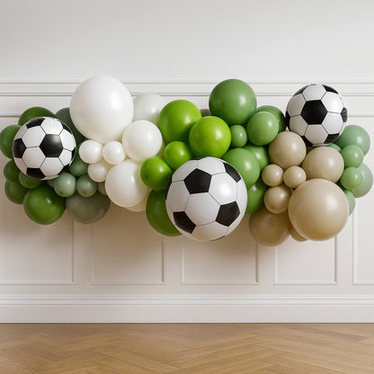 Balloon arch with soccer ball designs against a white wall.